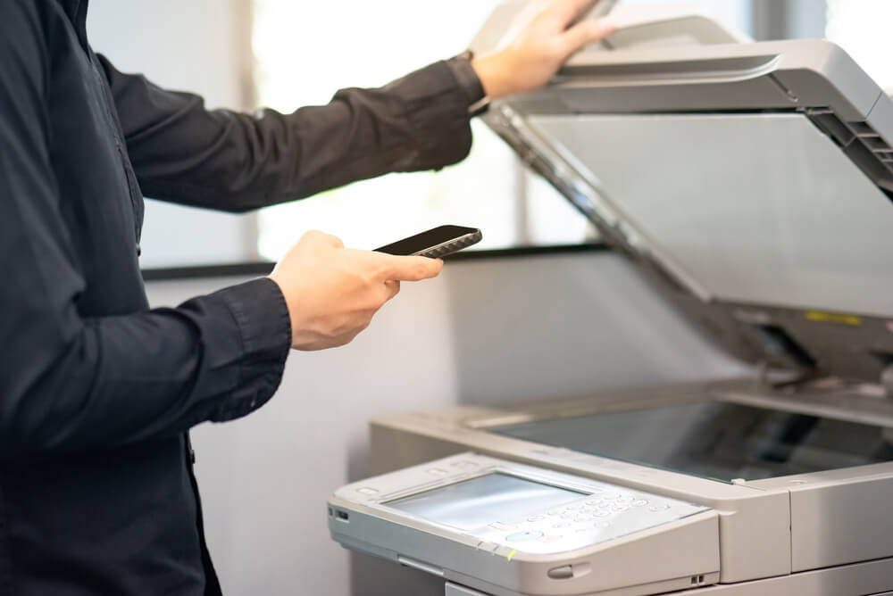 Using,Mobile,App,With,Photocopier.,Male,Hand,Holding,Smartphone,While